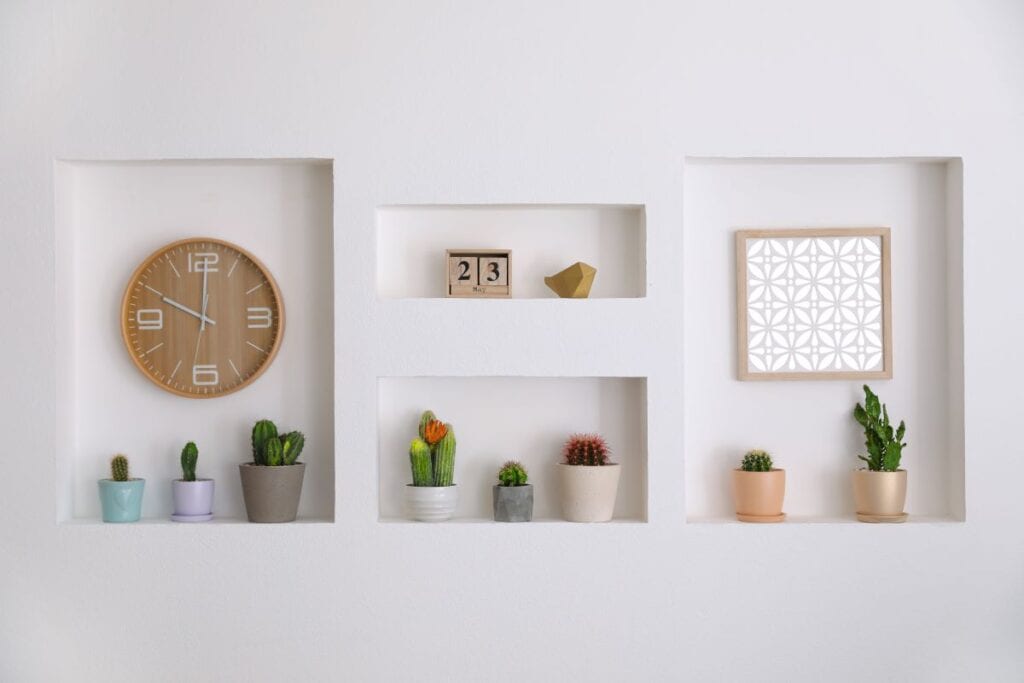 Potted cacti, clock, and picture frame in wall niches